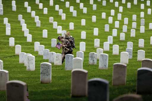A member of the 3rd U.S. Infantry Regiment places flags at the headstones of service members buried at Arlington National Cemetery, ahead of Memorial Day, Thursday, May 22, 2025, in Arlington, Va. (AP Photo/Julia Demaree Nikhinson)