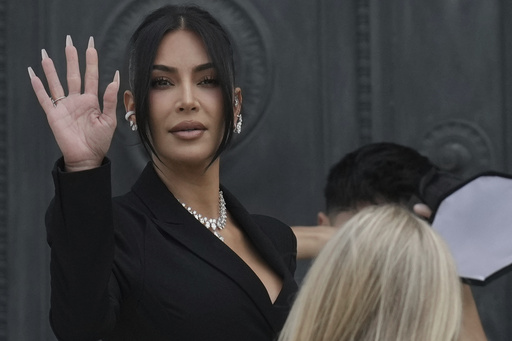 Kim Kardashian waves as she arrives to testify regarding a robbery of millions of dollars in jewels from her Paris hotel room in 2016, in Paris, Tuesday, May 13, 2025. (AP Photo/Aurelien Morissard)