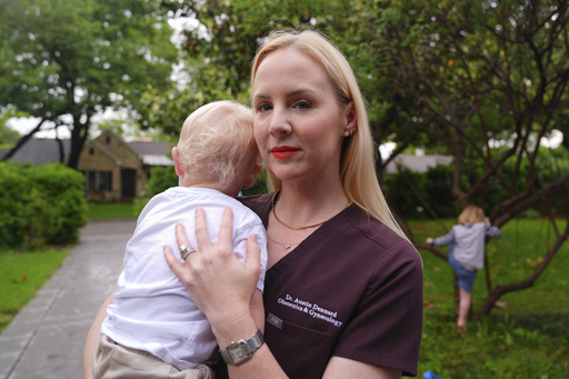 Dr. Austin Dennard holds her son as she poses for a portrait at her home in Dallas, Friday, May 2, 2025. (AP Photo/LM Otero)