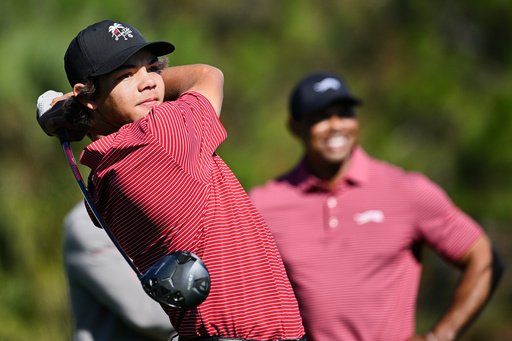 FILE- Charlie Woods tees off on the fifth hole as his father Tiger Woods watches during the final round of the PNC Championship golf tournament, Sunday, Dec. 22, 2024, in Orlando, Fla. (AP Photo/Phelan M. Ebenhack, File)