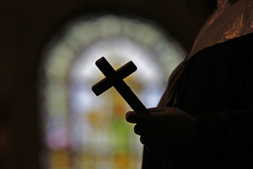 FILE - A silhouette of a crucifix and a stained glass window is seen inside a Catholic Church in New Orleans, Dec. 1, 2012. (AP Photo/Gerald Herbert, File)