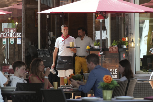 FILE - A waiter carries drinks, Friday, April 18, 2025, in Miami Beach, Fla. (AP Photo/Marta Lavandier, File)