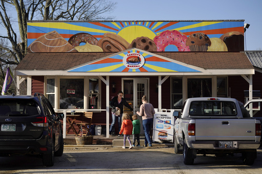 FILE - A customer holds the door for a family arriving at Leavitt's Country Bakery, Thursday, April 13, 2023, in Conway, N.H. Lawyers in a First Amendment lawsuit that pits a New Hampshire bakery owner against a town zoning ordinance over a large painting of doughnuts and other pastries are hoping that a judge can resolve the matter after voters didn't. (AP Photo/Robert F. Bukaty, File)