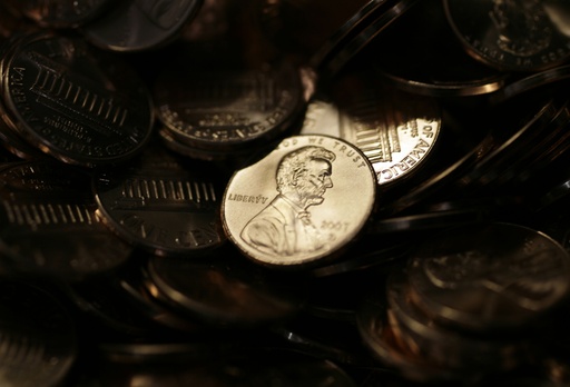 FILE - A lone penny is illuminated in a bin of completed pennies at the U.S. Mint in Denver on Wednesday, Aug. 15, 2007. (AP Photo/David Zalubowski, File)