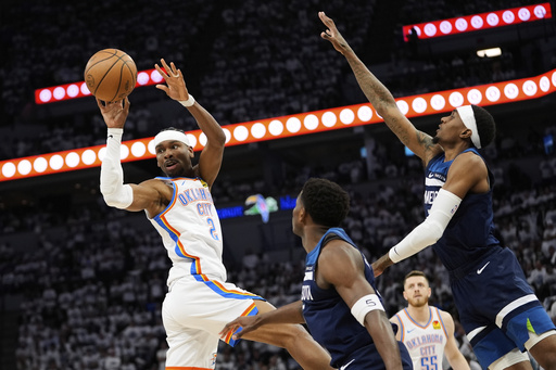 Oklahoma City Thunder guard Shai Gilgeous-Alexander (2) passes against Minnesota Timberwolves guard Anthony Edwards, center, and forward Jaden McDaniels, right, during the first half of Game 3 of the Western Conference finals of the NBA basketball playoffs, Saturday, May 24, 2025, in Minneapolis. (AP Photo/Abbie Parr)