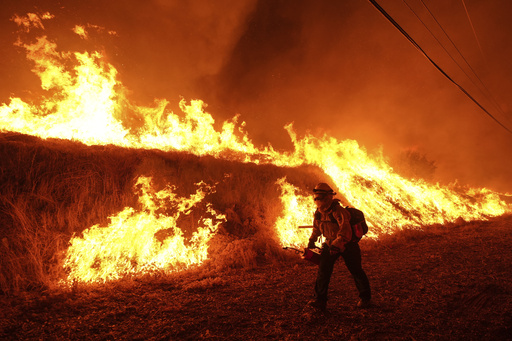 FILE - A firefighter carries a drip torch as he ignites a backfire against the Hughes Fire burning along a hillside in Castaic, Calif., Jan. 22, 2025. (AP Photo/Jae C. Hong, File)