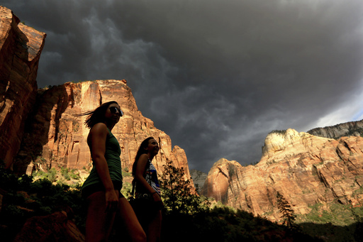FILE - Hikers look up at a fast moving storm as it makes its way through Zion National Park outside of Springdale, Utah, July 22, 2013. (AP Photo/Sandy Huffaker, File)