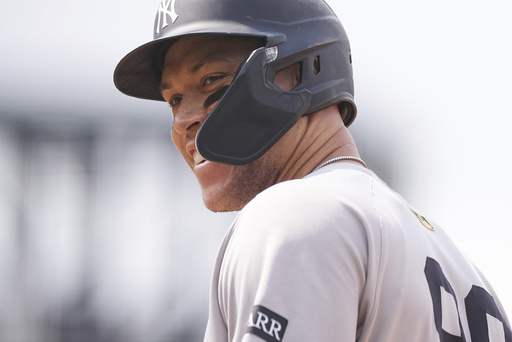 New York Yankees' Aaron Judge smiles as he steps on first base after being issued an intentional walk in the fifth inning of a baseball game against the Colorado Rockies, Saturday, May 24, 2025, in Denver. (AP Photo/David Zalubowski)