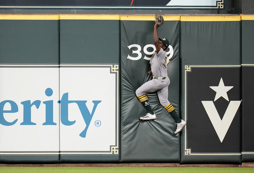 Athletics center fielder Denzel Clarke (1) tries to reach for Houston Astros' Jose Altuve's two-run home run during the fourth inning of a baseball game, Tuesday, May 27, 2025, in Houston. (AP Photo/Karen Warren)