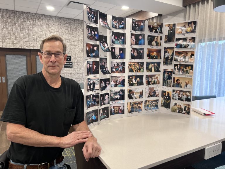Amateur photographer Dale Carter poses next to some of the images he has captured over the last two decades of physicists who visit the Black Hills and the Sanford Underground Research Facility.