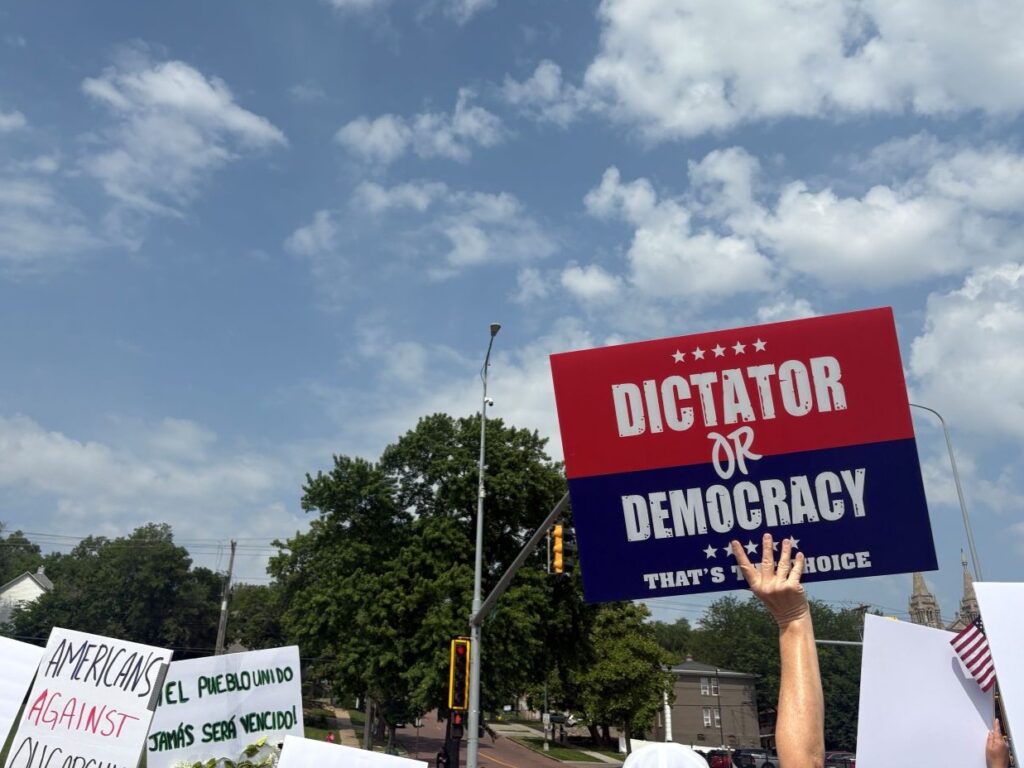 Demonstrators hold signs during a No Kings protest on June 14, 2025, in Sioux Falls. (Joshua Haiar/South Dakota Searchlight)