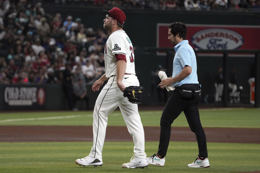 Arizona Diamondbacks pitcher Corbin Burnes, left, leaves a baseball game against the Washington Nationals in the fifth inning Sunday, June 1, 2025, in Phoenix. (AP Photo/Rick Scuteri)