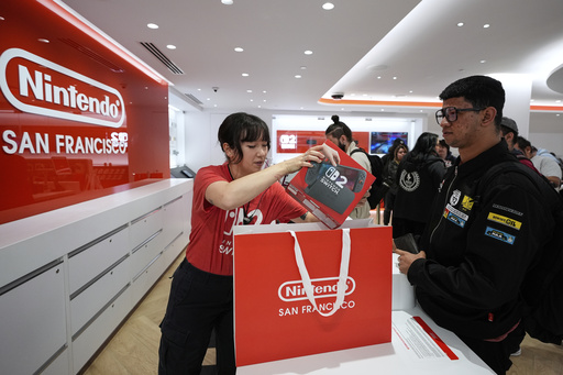 Nintendo specialist ambassador Cyan Chang, left, places a new Nintendo Switch 2 video game console into a bag for Ronald Diaz in San Francisco, Thursday, June 5, 2025. (AP Photo/Godofredo A. Vásquez)