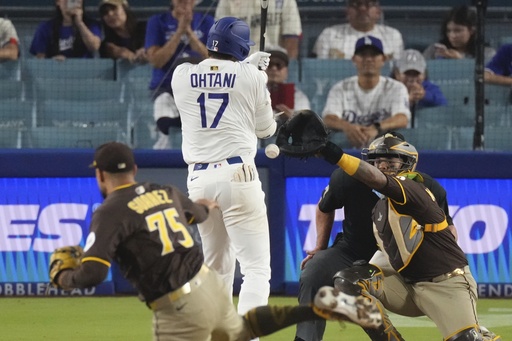 Los Angeles Dodgers' Shohei Ohtani, center is hit by a pitch thrown by San Diego Padres relief pitcher Robert Suarez, left as catcher Martin Maldonado watches during the ninth inning of a baseball game Thursday, June 19, 2025, in Los Angeles. (AP Photo/Mark J. Terrill)