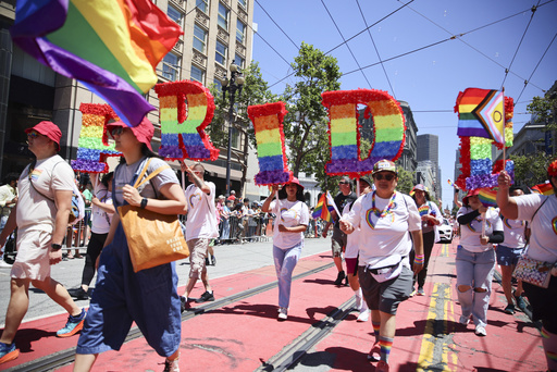 FILE - Revelers walk along Market Street during a Pride Parade, June 30, 2024, in San Francisco. (AP Photo/Ethan Swope, File)