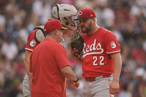 Cincinnati Reds pitching coach Derek Johnson, left, talks with catcher Tyler Stephenson, center, and starting pitcher Wade Miley (22) in the third inning of a baseball game in Cleveland, Monday, June 9, 2025. (AP Photo/Sue Ogrocki)