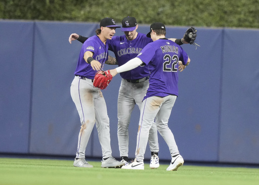 Colorado Rockies left fielder Jordan Beck, left, center fielder Brenton Doyle, center and right fielder Mickey Moniak (22) celebrate after the Rockies defeated the Miami Marlins in a baseball game, Tuesday, June 3, 2025, in Miami. (AP Photo/Lynne Sladky)