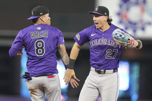 Colorado Rockies shortstop Orlando Arcia (8) and left fielder Jordan Beck (27) high-five after the Rockies defeated the Miami Marlins in a baseball game, Wednesday, June 4, 2025, in Miami. (AP Photo/Lynne Sladky)
