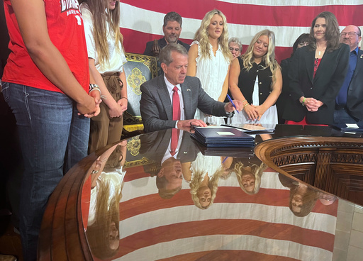 Nebraska Gov. Jim Pillen is flanked by supporters Wednesday, June 4, 2025 as he signs into law a bill banning transgender athletes from girls' sports. (AP Photo/Margery Beck)