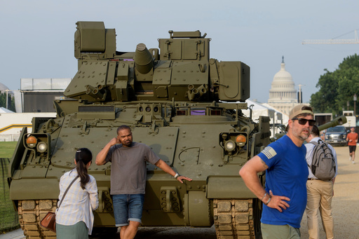 People pass by and take photos with a tank, parked on the National Mall, during preparations for an upcoming military parade commemorating the Army's 250th anniversary and coinciding with President Donald Trump's 79th birthday, Thursday, June 12, 2025, in Washington. (AP Photo/Rod Lamkey, Jr.)