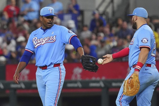 Texas Rangers first base Jake Burger (21) hands the baseball game ball to starting pitcher Kumar Rocker during the fifth inning against the Chicago White Sox, Sunday, June 15, 2025, in Arlington, Texas. (AP Photo/LM Otero)