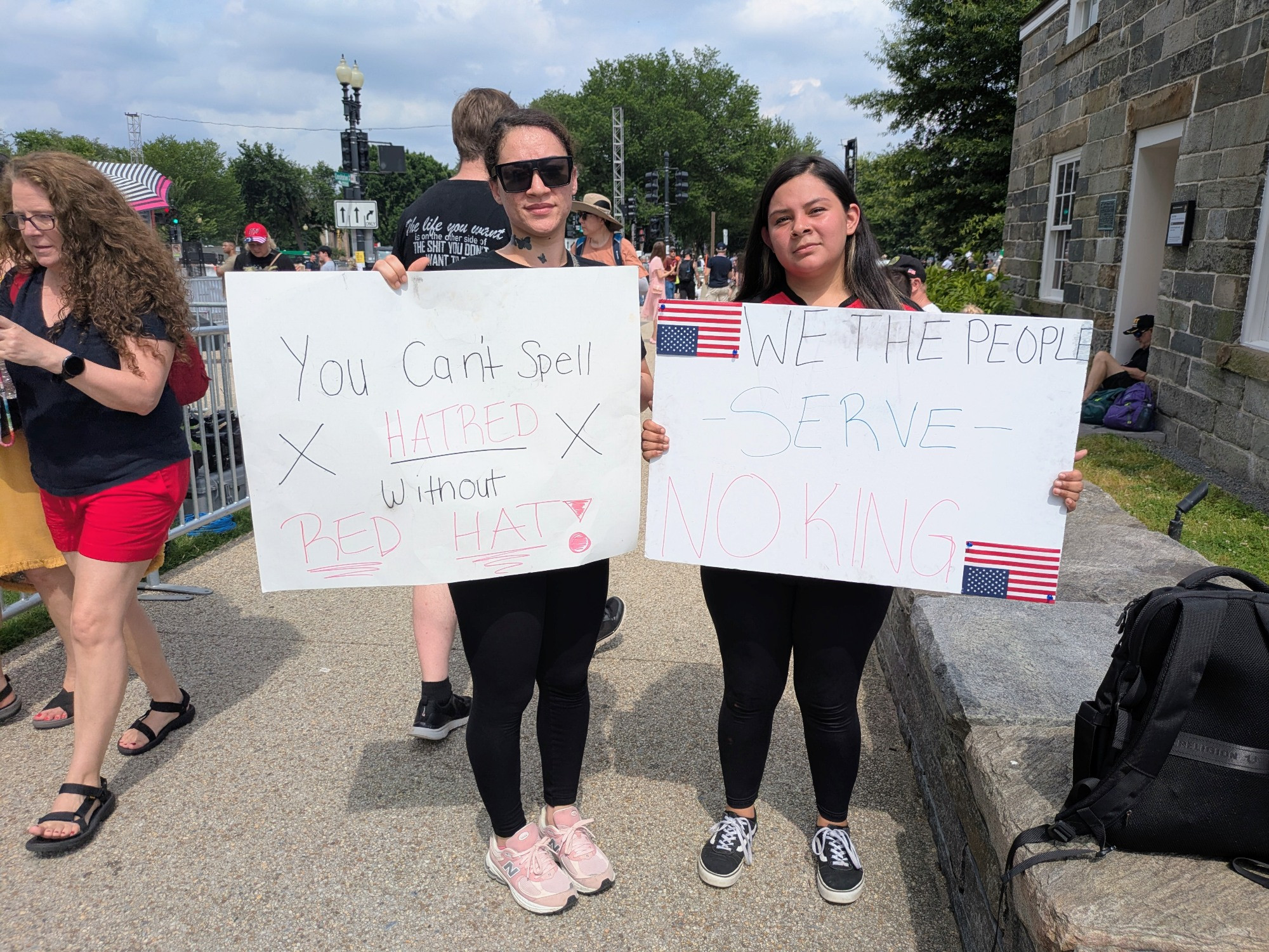 Angelica Zetino, 24, and Shoshauna Brooks, 27, from Rockville and Gaithersburg, Maryland, stood out among the crowd as they carried signs protesting Trump's administration, particularly recent immigration raids, at the U.S. Army parade in Washington, D.C. on June 14, 2025. (Photo by Ashley Murray/States Newsroom)
