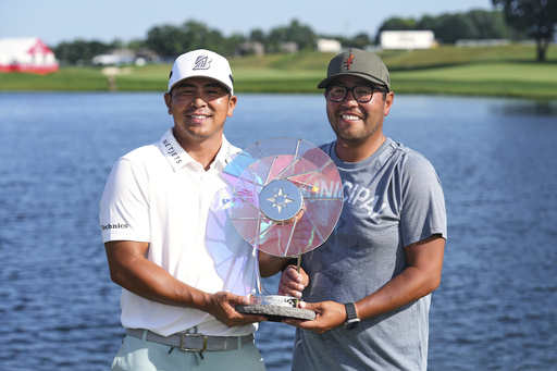 Kurt Kitayama, left, and his caddie, Daniel Kitayama, hold their trophy after winning the 3M Open golf tournament at the Tournament Players Club Sunday, July 27, 2025, in Blaine, Minn. (AP Photo/Abbie Parr)