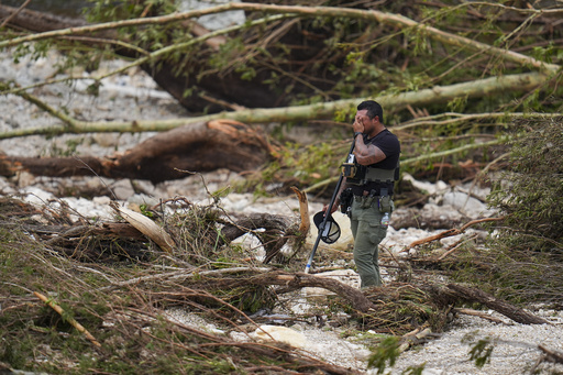 A Sheriff's deputy pauses while combing through the banks of the Guadalupe River near Camp Mystic, Saturday, July 5, 2025, in Hunt, Texas, after a flash flood swept through the area. (AP Photo/Julio Cortez)