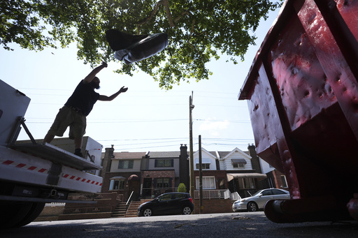 A man tosses trash at a garbage collection site, Thursday, July 3, 2025, in Philadelphia. (AP Photo/Matt Slocum)