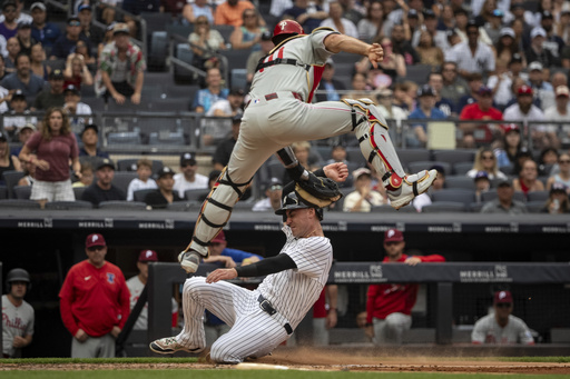 New York Yankees' Cody Bellinger, bottom, is tagged out at home plate by Philadelphia Phillies catcher J.T. Realmuto, top, during the third inning of a baseball game, Sunday, July 27, 2025, in New York. (AP Photo/Angelina Katsanis)
