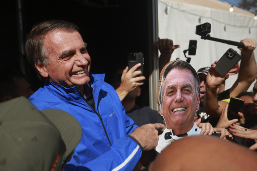 Brazil's former President Jair Bolsonaro points a photo of him during a motorcycle caravan by supporters to protest the Supreme Court trial where he faces charges for alleged involvement in a 2022 coup attempt, in Brasília, Brazil, Tuesday, July 29, 2025. (AP Photo/Luis Nova)