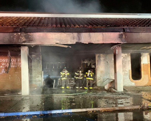 This photo provided by the San Jose Fire Department shows firefighters responding to a fire burning after a car crashed into a Post Office, early Sunday, July 20, 2025, in San Jose, Calif. (San Jose Fire Department via AP)