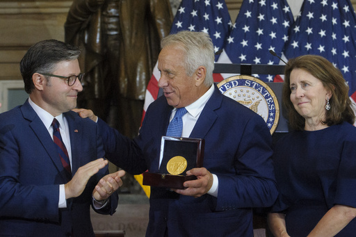 Three-time Tour de France winner Greg LeMond, center, is joined by his wife Kathy LeMond, right, while being presented the Congressional Gold Medal by Speaker of the House Mike Johnson, R-La., left, during a ceremony at the Capitol, Wednesday, July 9, 2025, in Washington. (AP Photo/Rod Lamkey, Jr.)