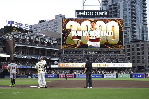 San Diego Padres' Manny Machado, third from left, reacts after hitting a single, his 2000th career hit, during the fourth inning of a baseball game against the Arizona Diamondbacks, Monday, July 7, 2025, in San Diego. (AP Photo/Orlando Ramirez)