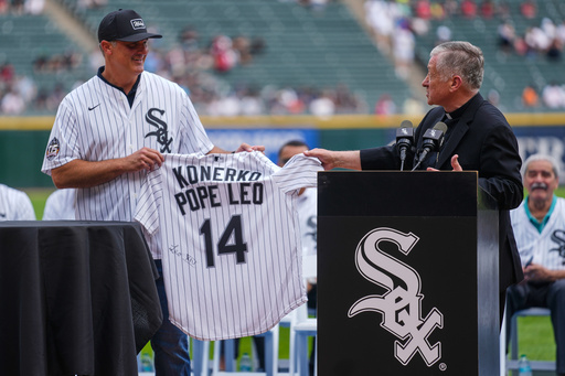 Cardinal Blase Cupich, right, presents former White Sox player Paul Konerko with a jersey signed by Pope Leo XIV during a ceremony honoring the 2005 World Series Champions before a baseball game between the Cleveland Guardians and Chicago White Sox, Saturday, July 12, 2025, in Chicago. (AP Photo/Erin Hooley)