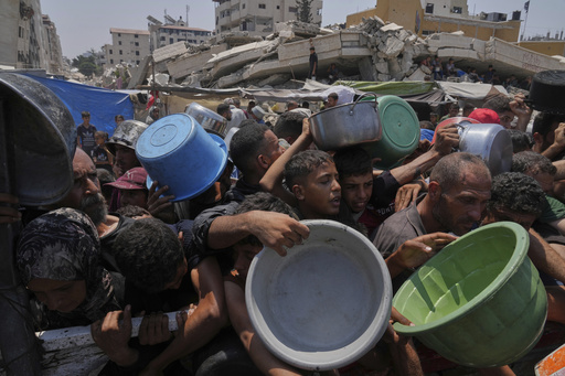 Palestinians struggle to get donated food at a community kitchen, in Gaza City, northern Gaza Strip, Saturday, July 26, 2025. (AP Photo/Abdel Kareem Hana)