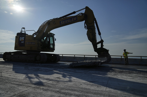 A demolition crew removes a slab of concrete from the remaining portions of the Francis Scott Key Bridge, Wednesday, July 30, 2025, in Baltimore. (AP Photo/Stephanie Scarbrough)