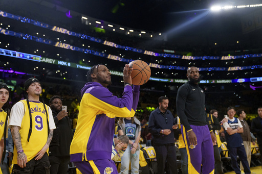 FILE - Los Angeles Lakers guard Bronny James, left, and forward LeBron James warm up before an NBA basketball game against the Minnesota Timberwolves, Oct. 22, 2024, in Los Angeles. (AP Photo/Eric Thayer, File)