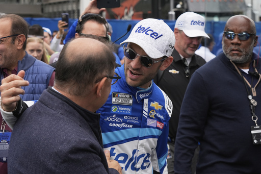 Daniel Suarez, center greets a man before a NASCAR Cup Series auto race at Hermanos Rodríguez race track in Mexico City, Sunday, June 15, 2025. (AP Photo/Fernando Llano)