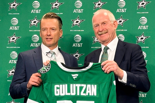 Dallas Stars new head coach Glen Gulutzan, left, and general manager Jim Nill hold up a team jersey after Gulutzan was introduced during an NHL hockey news conference, Wednesday, July 2, 2025, at the American Airlines Center in Dallas. (AP Photo/Stephen Hawkins)