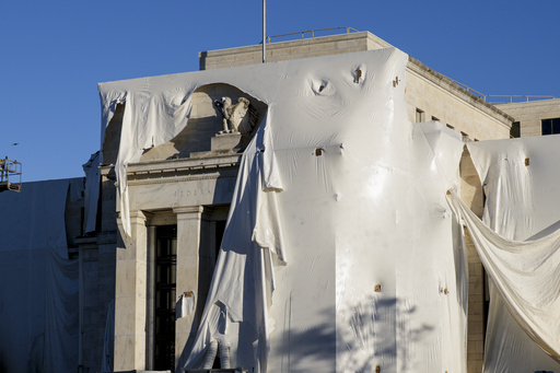 FILE - The sculpture of an eagle looks out from behind protective construction wrapping on the facade as the Federal Reserve Board Building undergoes both interior and exterior renovations, in Washington, Monday, Oct. 23, 2023. (AP Photo/J. Scott Applewhite, File)