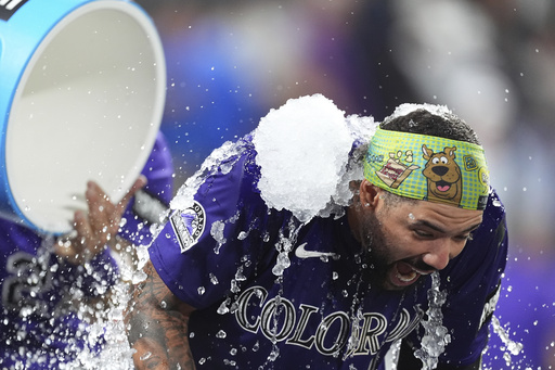 Colorado Rockies' Warming Bernabel, right, is doused by teammate Jordan Beck, back left, after hitting a walk-off RBI single off Los Angeles Dodgers relief pitcher Justin Wrobleski in the ninth inning of a baseball game Monday, Aug. 18, 2025, in Denver. (AP Photo/David Zalubowski)