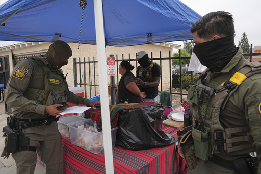 A woman is detained by U.S. Border Patrol agents outside a Home Depot Friday, Aug. 15, 2025, in Los Angeles. (AP Photo/Gregory Bull)