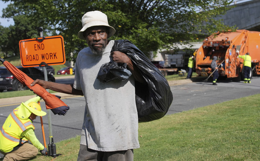 George, 67, walks away with what's left of his belongings, after the city put his mattress and other belongings in a garbage truck, Thursday, Aug. 14, 2025, in Washington. (AP Photo/Jacquelyn Martin)