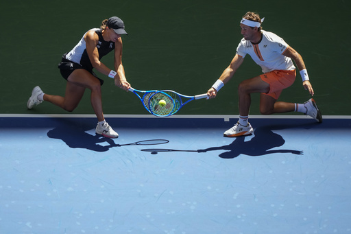 Casper Ruud, of Norway, left, plays a shot as partner Iga Swiatek, left, of Poland, covers during their mixed doubles match at the U.S. Open tennis championships, Tuesday, Aug. 19, 2025, in New York. (AP Photo/Yuki Iwamura)