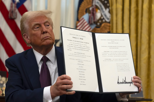 FILE - President Donald Trump holds up a signed executive order relating to clemency for anti-abortion protesters as he signs executive orders in the Oval Office of the White House, Jan. 23, 2025, in Washington. (AP Photo/Ben Curtis, File)