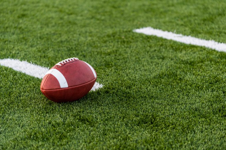 A brown leather american football on a green playing field