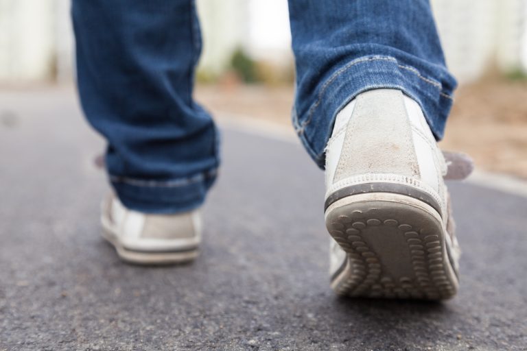 Teenager walking in sport shoes on pavement in autumn day