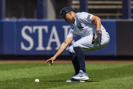 New York Yankees outfielder Giancarlo Stanton picks up a ball hit by Houston Astros' Jesús Sánchez (4) during the fourth inning of a baseball game against the Houston Astros, Saturday, Aug. 9, 2025, in New York. (AP Photo/Yuki Iwamura)