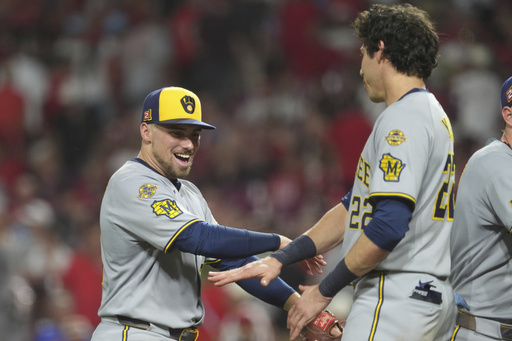 Milwaukee Brewers' Caleb Durbin, left, and Milwaukee Brewers' Christian Yelich, right, celebrate at the conclusion of a baseball game game against the Cincinnati Reds, Friday, Aug. 15, 2025, in Cincinnati. (AP Photo/Kareem Elgazzar)